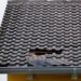Close up of a roof of a yellow house with black tiles.